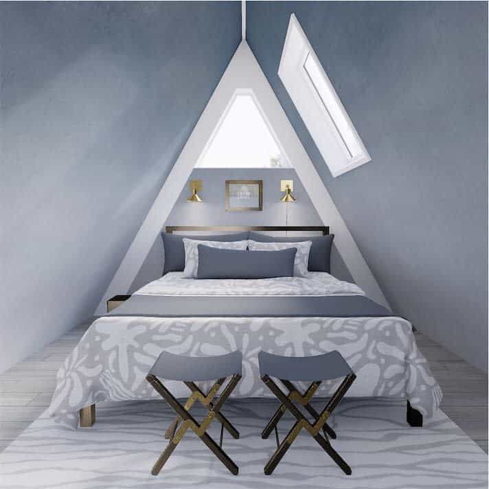 Stylish attic bedroom with an A-frame design, soft blue walls, and gold accents. A cozy bed setup with modern decor creates a serene retreat.