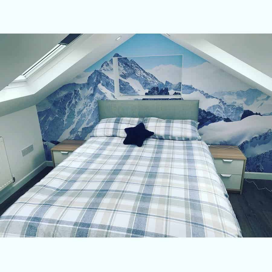 Cozy attic bedroom with a stunning mountain mural, skylights, and soft plaid bedding. A nature-inspired retreat with a calming atmosphere.