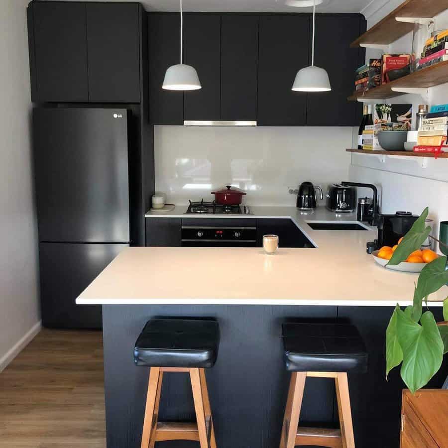 Modern kitchen with a black and white breakfast bar, sleek dark cabinetry, wooden barstools with leather seats, and open shelving for a stylish touch