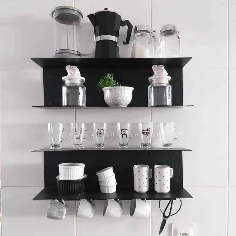 Black kitchen shelves with various items: a coffee maker, jars, glasses, bowls, mugs, and a small plant, all neatly organized