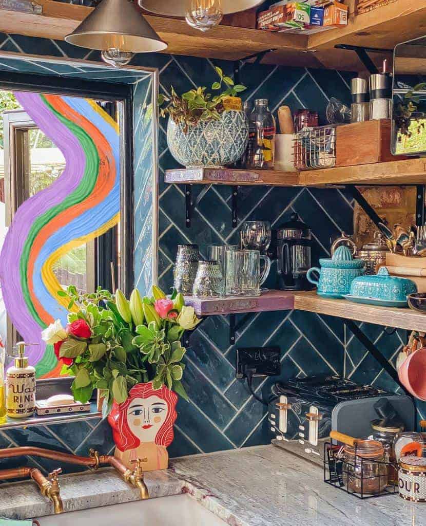 Eclectic kitchen with wooden floating shelves, blue tile backsplash, colorful decor, and open shelving for glassware and spices