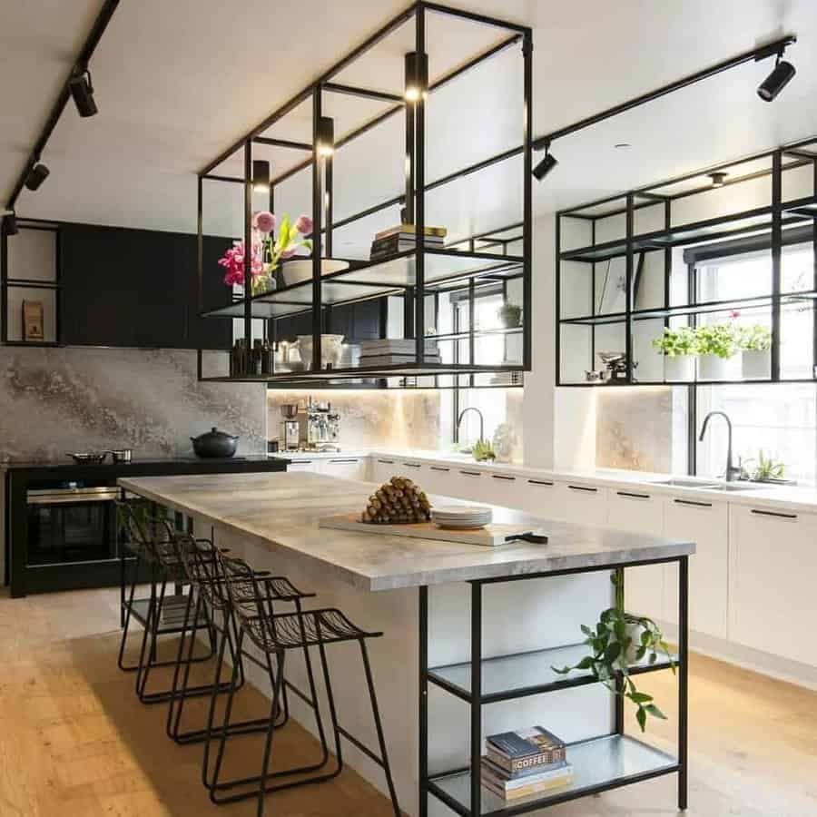 Modern kitchen with a large island, barstools, pendant lighting, and a black and white color scheme featuring open shelving with plants and decor