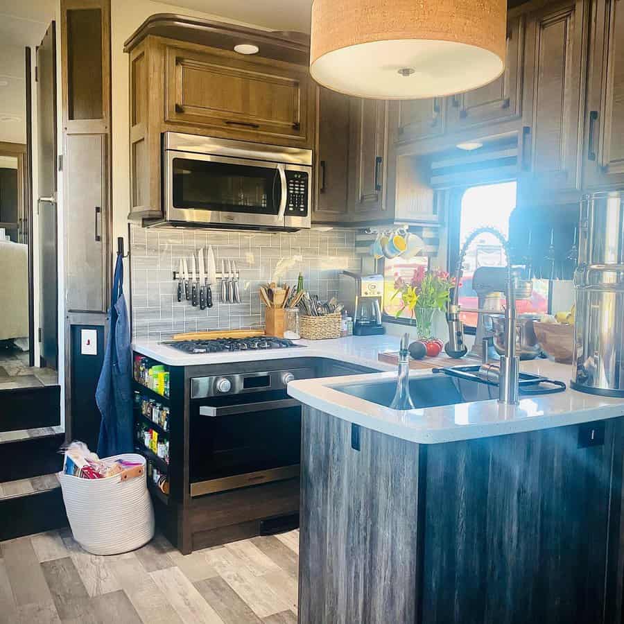 Modern RV kitchen with wood cabinetry, a large island sink, built-in spice storage, a magnetic knife strip, and a cozy, functional layout.