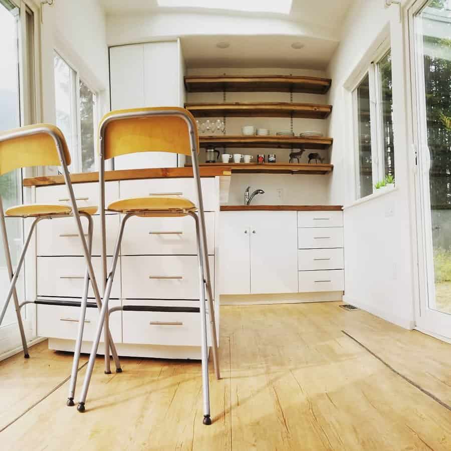 Bright tiny house kitchen with curved shelves and bar chairs