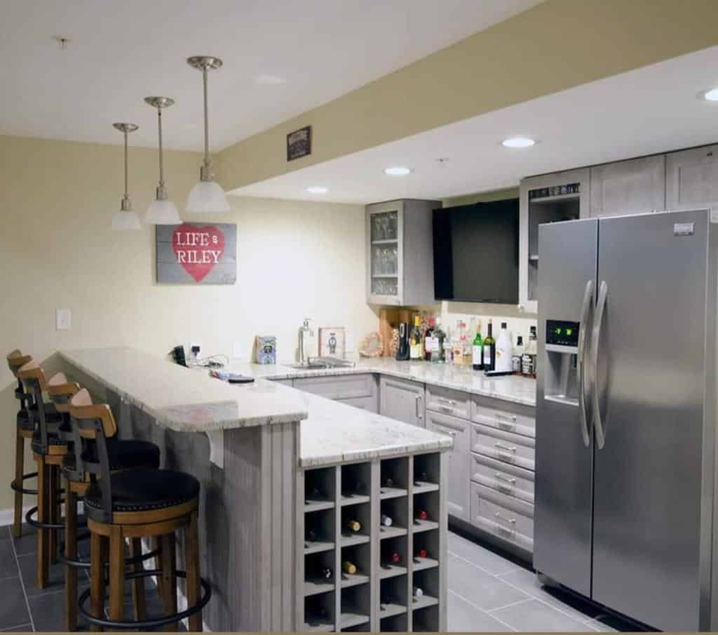 Cozy basement bar with a built-in wine rack, gray cabinetry, a marble countertop, and pendant lighting for a stylish and functional space