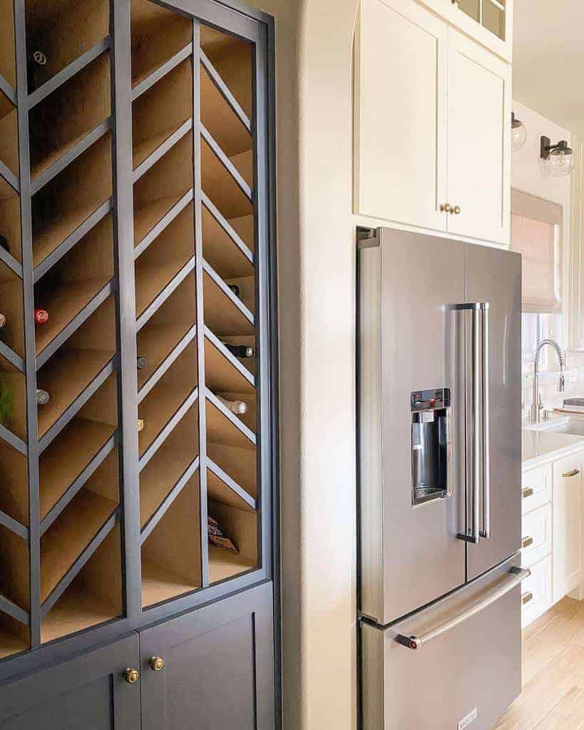 Stylish kitchen with a built-in chevron wine rack, navy cabinetry, and a stainless steel refrigerator for a modern and functional design