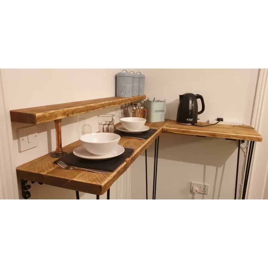 Compact wooden breakfast bar with two place settings, cups, and a kettle on the side