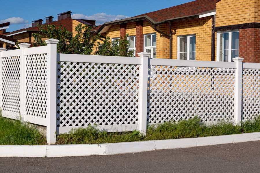 White lattice fence in front of yellow house