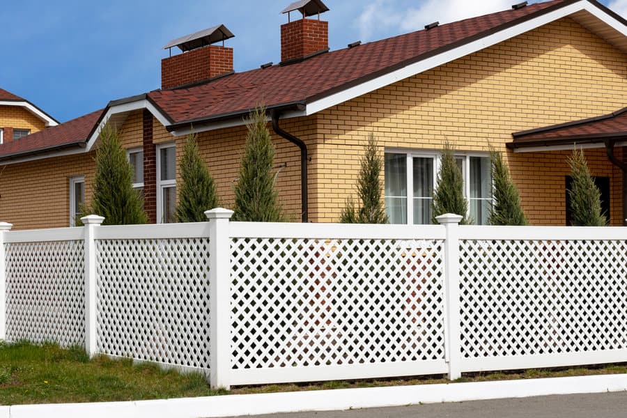 White lattice fence in front of brick house