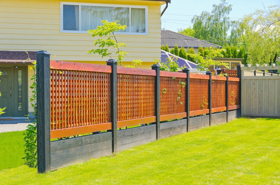 Red lattice fence with black posts and green lawn