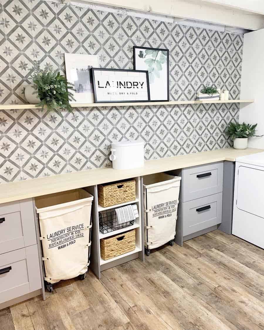 Stylish basement laundry room with patterned tile backsplash, built-in storage, rolling laundry bins, and decorative shelving for a chic and functional space.