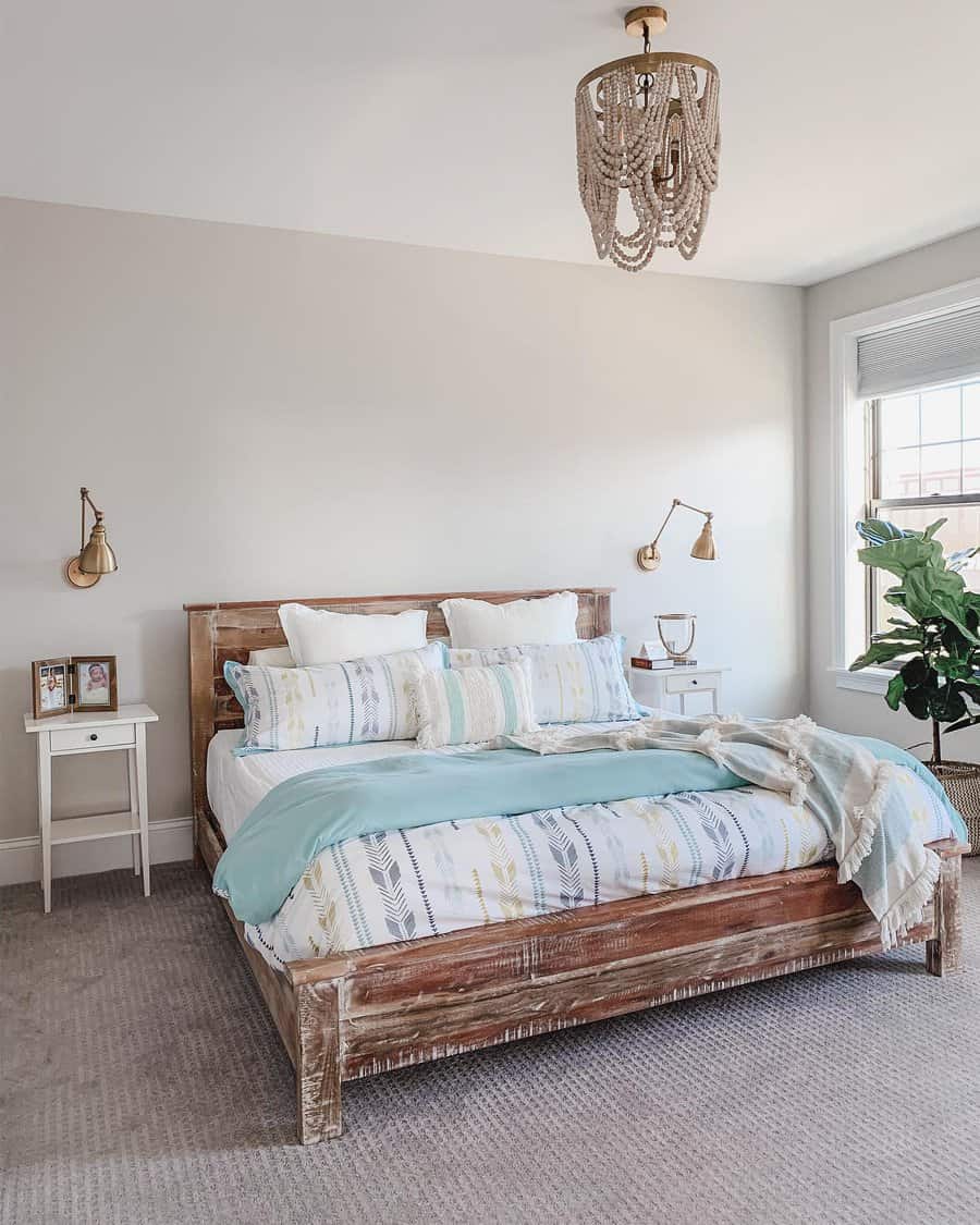 A cozy bedroom with a wooden bed, patterned bedding, turquoise throw, two nightstands, and a potted plant by a large window