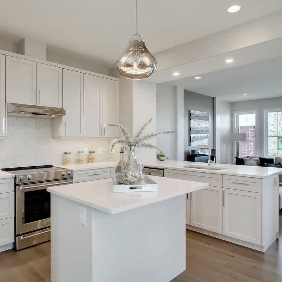 Modern kitchen with white cabinets, island, stainless appliances, and glass pendant light