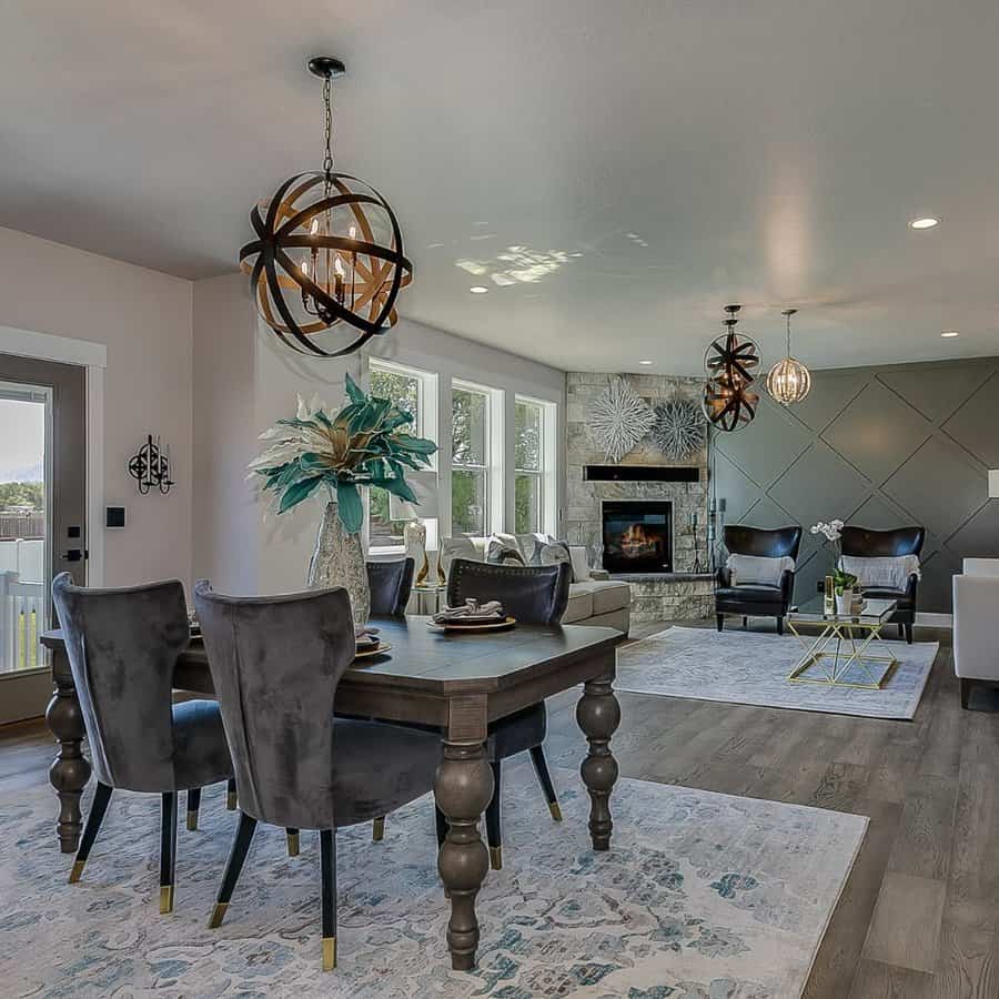 Modern open-concept living space with a dining table, dark chairs, textured walls, large windows, fireplace, and geometric light fixtures