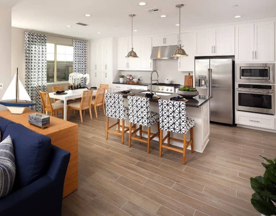 Bright open floor plan with a white kitchen, patterned barstools, navy accents, and a cozy dining area with natural light