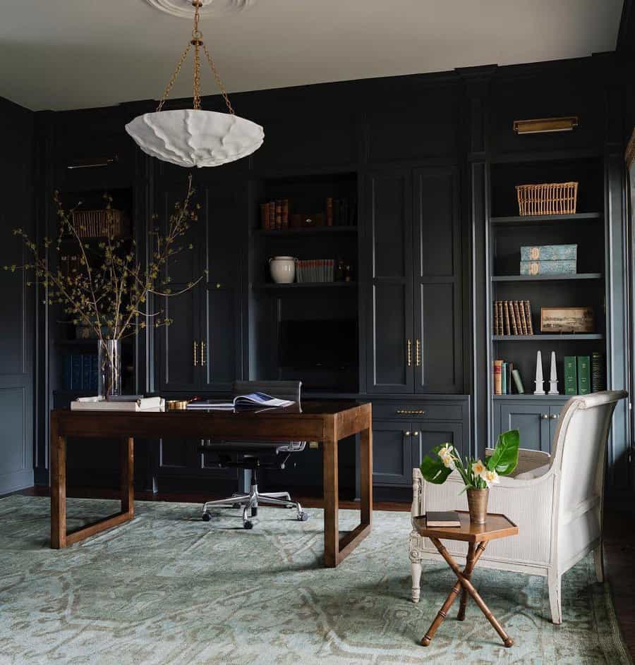 Elegant dark home office with wooden desk, white chair, bookshelves, potted plants, and a hanging light fixture