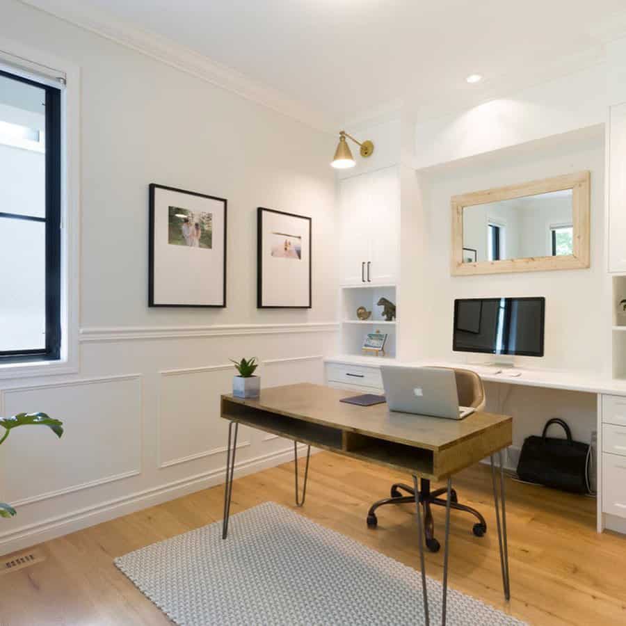 Minimalist home office featuring a wooden desk, laptop, wall art, and built-in shelves with bright lighting and natural wood flooring