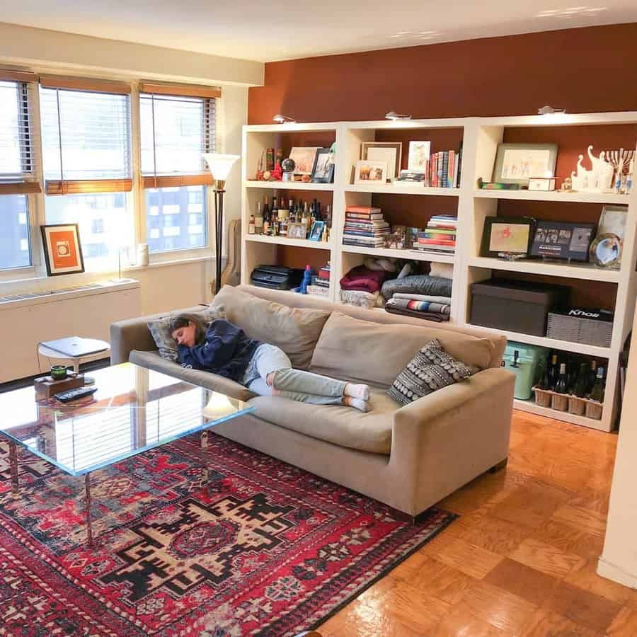 A cozy living room with built-in bookshelves, warm lighting, and a beige sofa, creating a functional and inviting space with smart storage