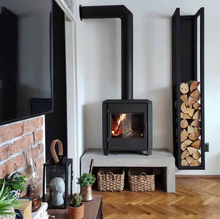 Modern wood stove on a concrete hearth with a sleek black chimney, built-in firewood storage, and cozy rustic decor for a stylish ambiance.