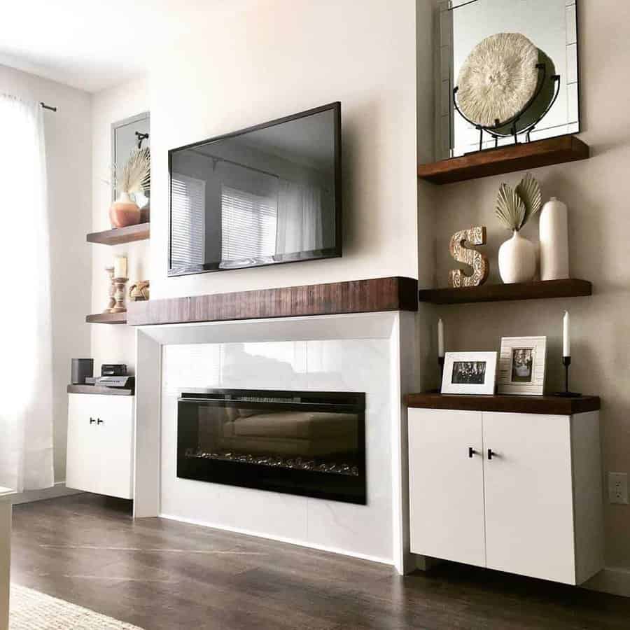 Modern living room with wall-mounted TV, electric fireplace, chic shelves with decor, and white cabinets on a wooden floor