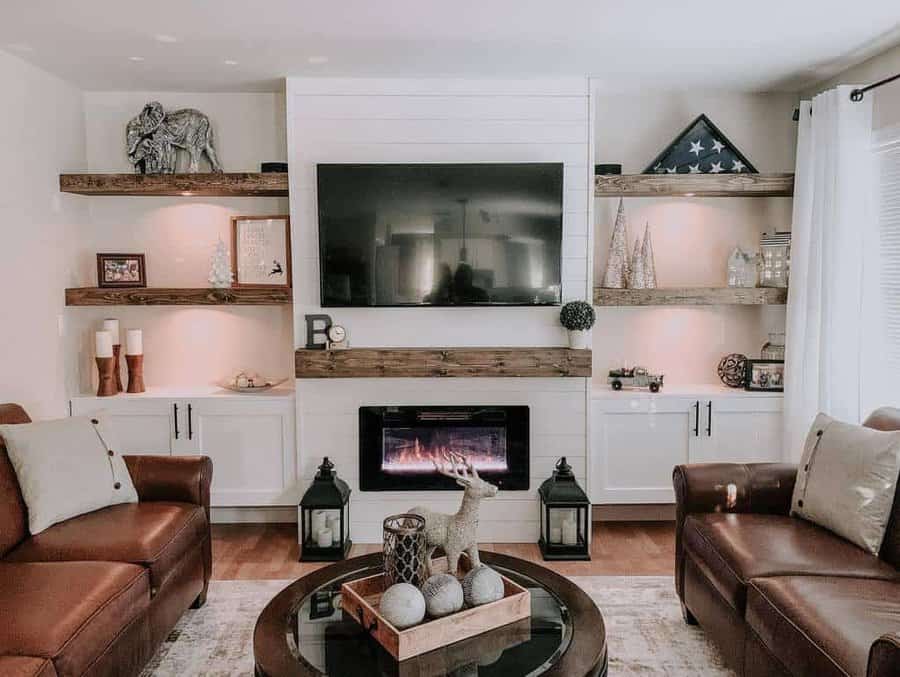 Cozy living room with rustic wooden floating shelves, a fireplace, built-in cabinets, and warm decorative lighting around a TV