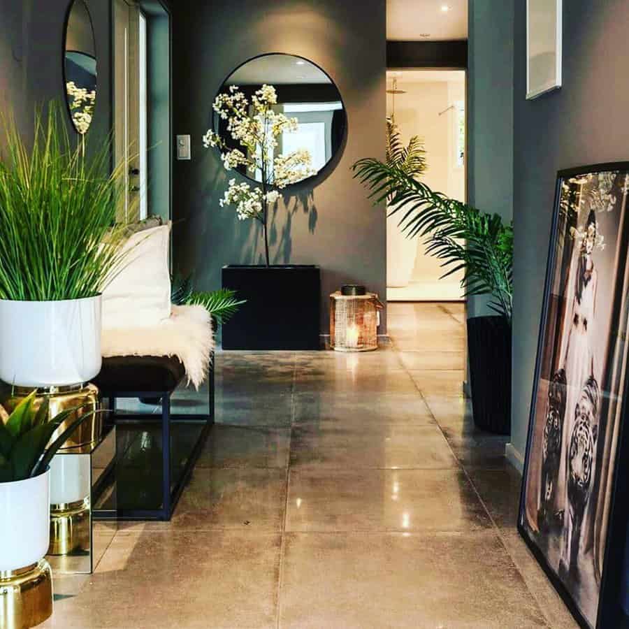 Sophisticated entryway with a sleek bench, lush greenery, modern decor, and a round mirror, creating a luxurious and inviting ambiance