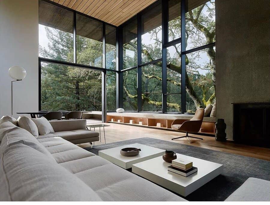 Modern living room with large windows and forest view