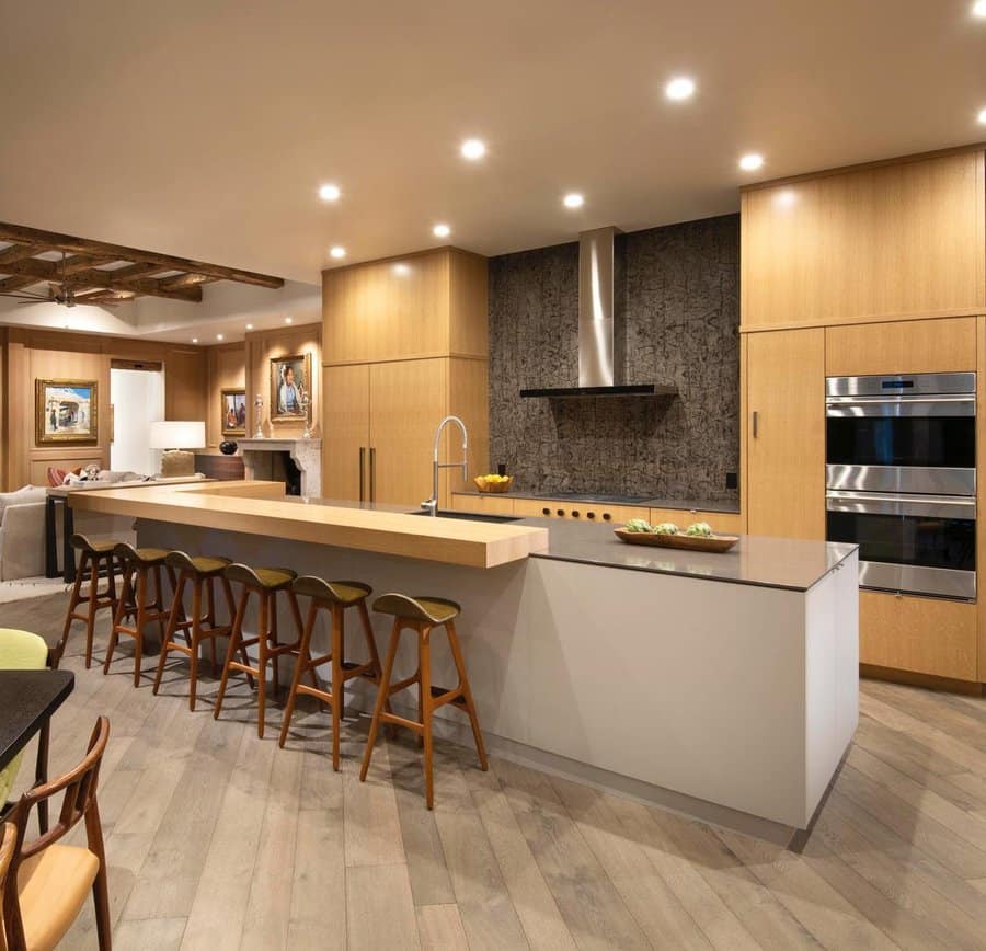 Modern kitchen with island, wooden cabinets, bar stools, and built-in appliances