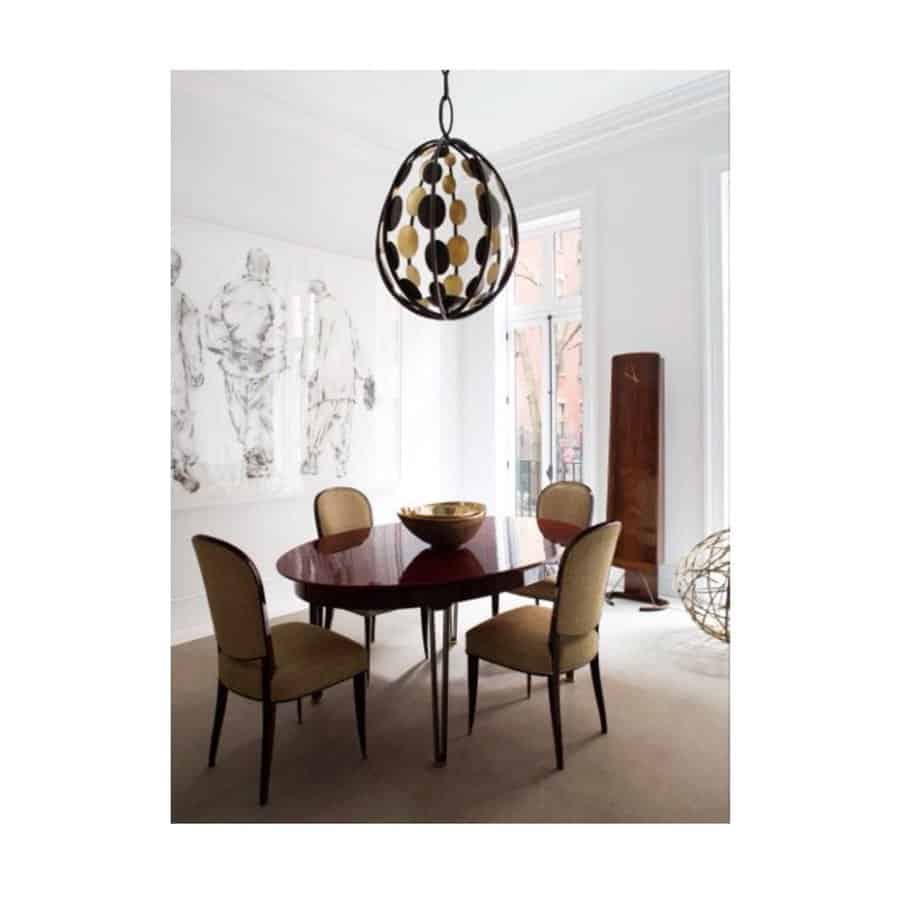 Modern dining room with a circular table, four beige chairs, and a patterned pendant light; abstract wall art and large windows