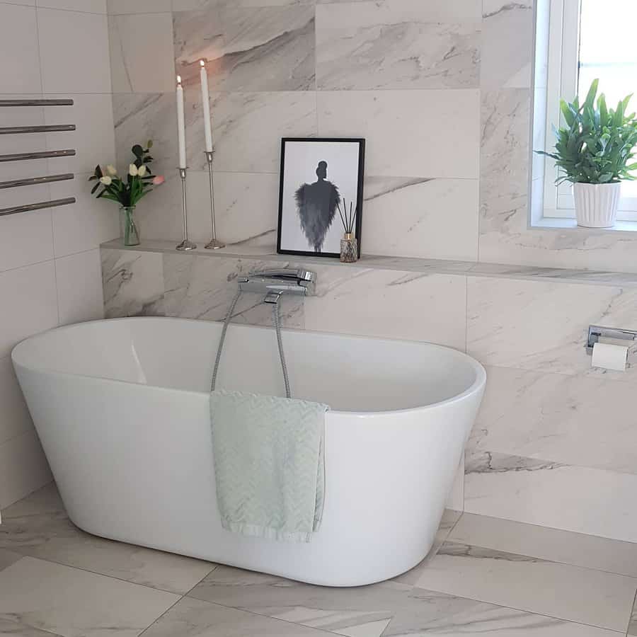 Elegant white tub with marble tiles and decorative accents