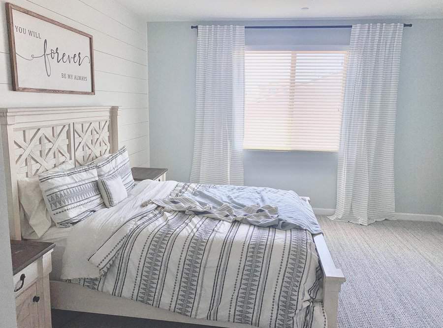 Bright bedroom with a striped bedspread, a carved headboard, striped curtains, and a wall sign reading "You Will Forever Be My Always"