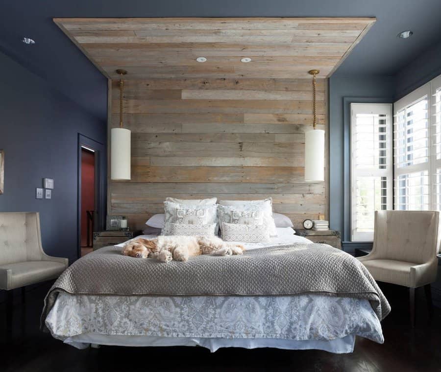 Modern rustic master bedroom with a reclaimed wood accent wall, dark moody tones, and cozy layered bedding, creating a stylish and inviting retreat