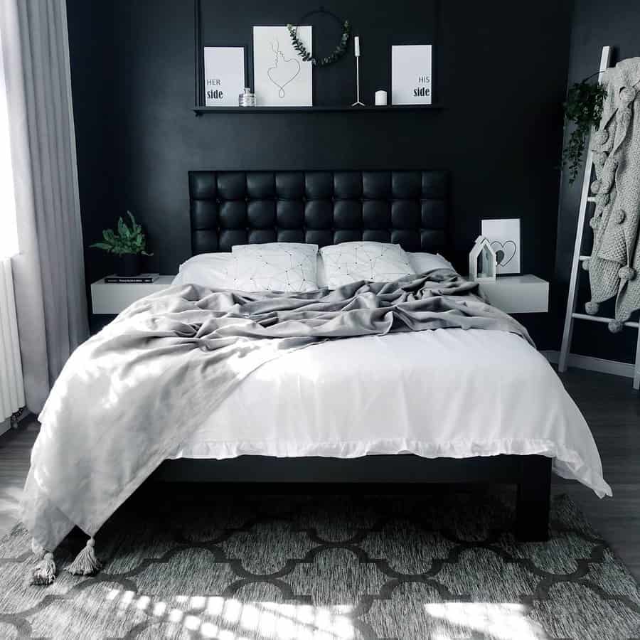 Stylish black and white bedroom with a tufted headboard, gray throw blanket, and decorative shelf above the bed