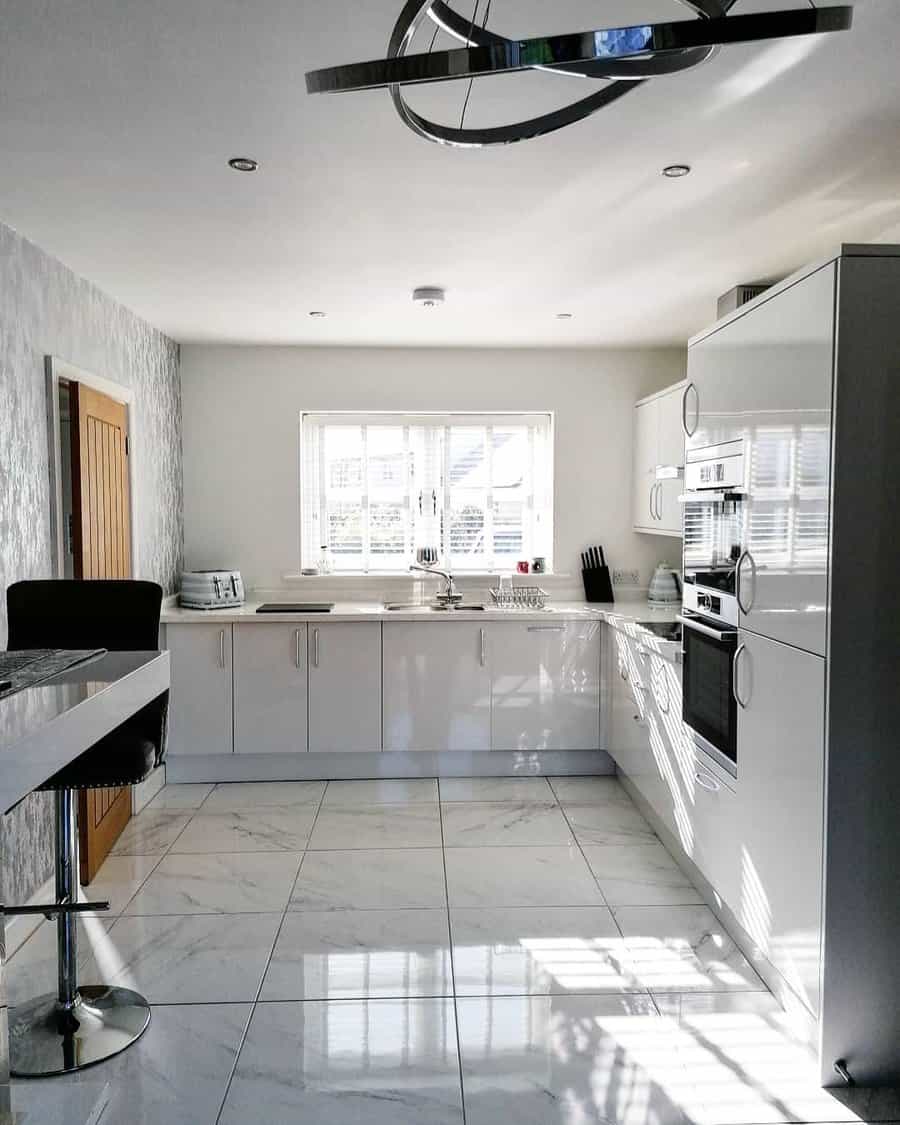 Bright kitchen with large window and glossy marble tiles