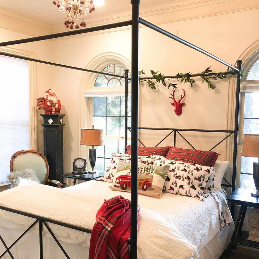 Festive canopy bed with a black metal frame, holiday-themed bedding, plaid pillows, and Christmas décor, creating a cozy and cheerful bedroom