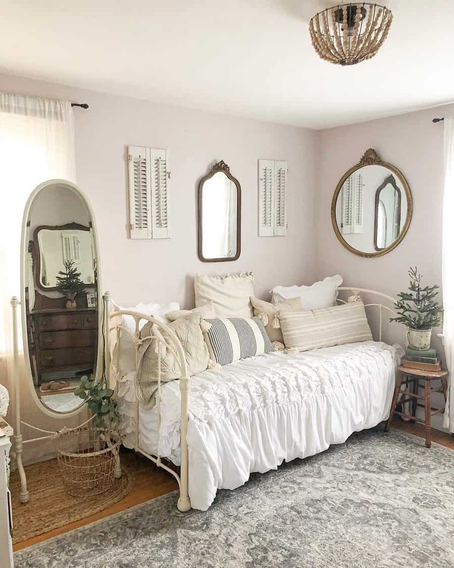 Vintage-inspired metal daybed with ruffled white bedding, soft neutral pillows, and antique mirrors, creating a cozy and elegant farmhouse retreat