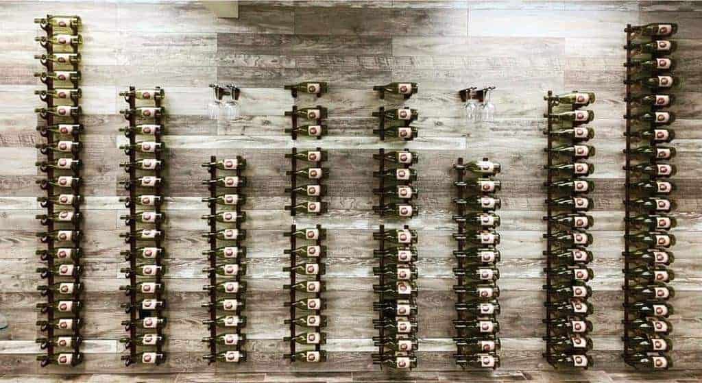 A wall display of wine bottles arranged in vertical rows on a wooden background