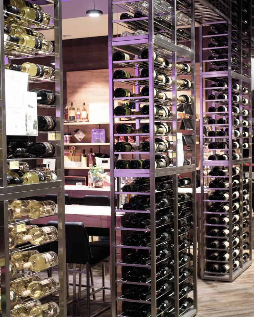 Wine racks filled with bottles in a modern store setting with tables and chairs