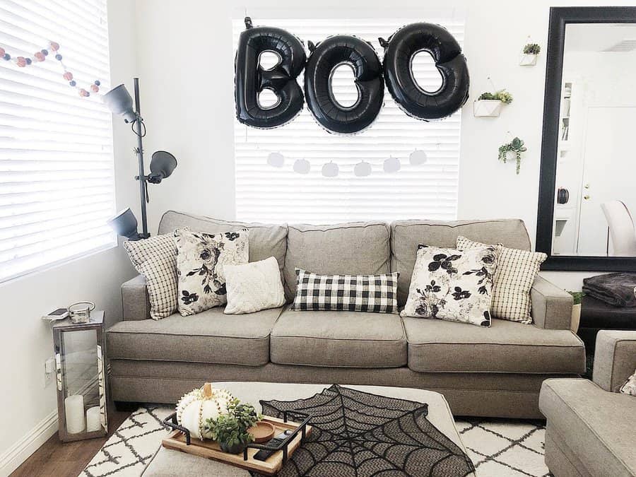 Cozy living room with "BOO" balloons and Halloween-themed decorations on the couch