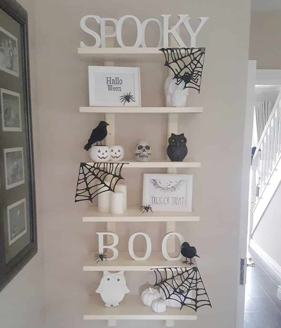 A Halloween-themed wall shelf with decorations like spiders, webs, and skulls