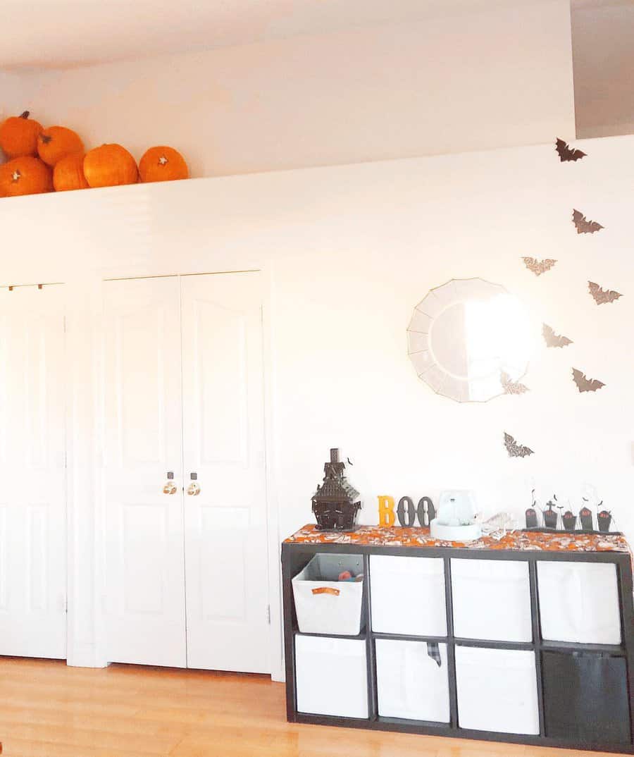 A Halloween-themed room with bats on the wall and pumpkins above a closet