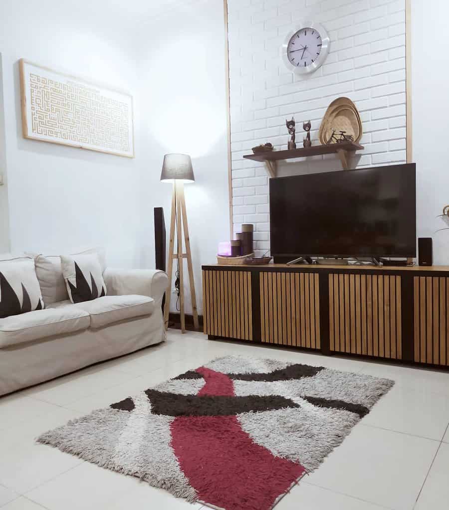 Minimalist living room with a sofa, TV, rug, and wall clock above the TV stand