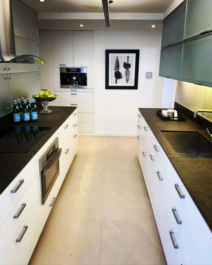 Modern kitchen with white cabinets, black countertops, and framed artwork on the wall