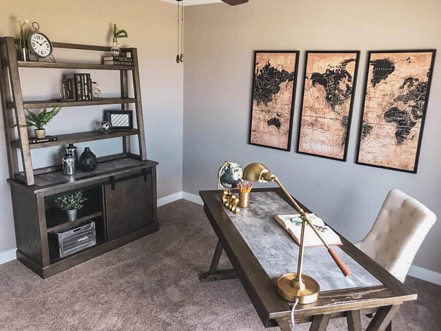 Home office with a wooden desk, globe, lamp, and notebook: Three world map frames on the wall and a shelf with books and decor items