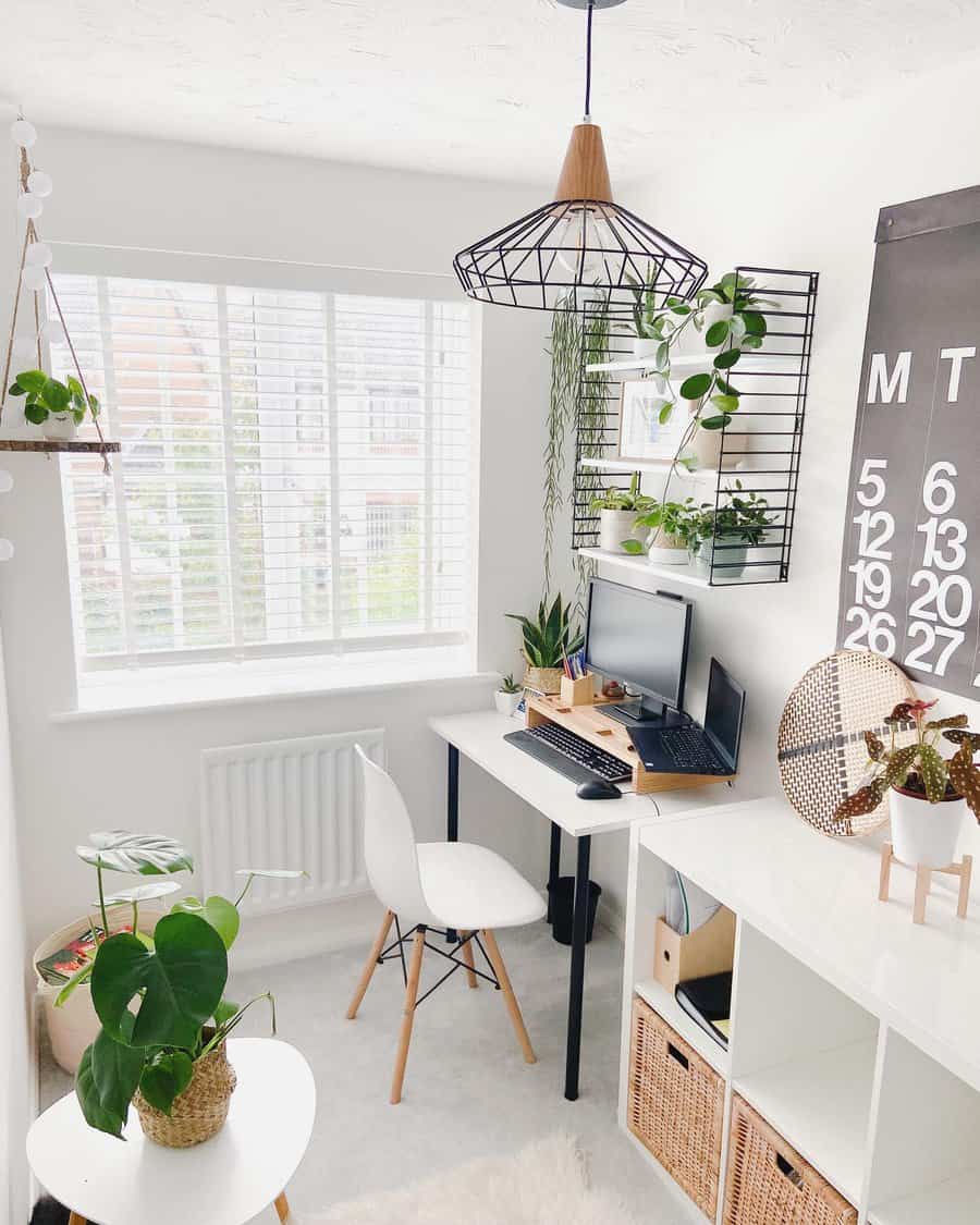 Minimalist home office with a small desk, chair, and computer beneath a large calendar; decor includes plants and a geometric light fixture