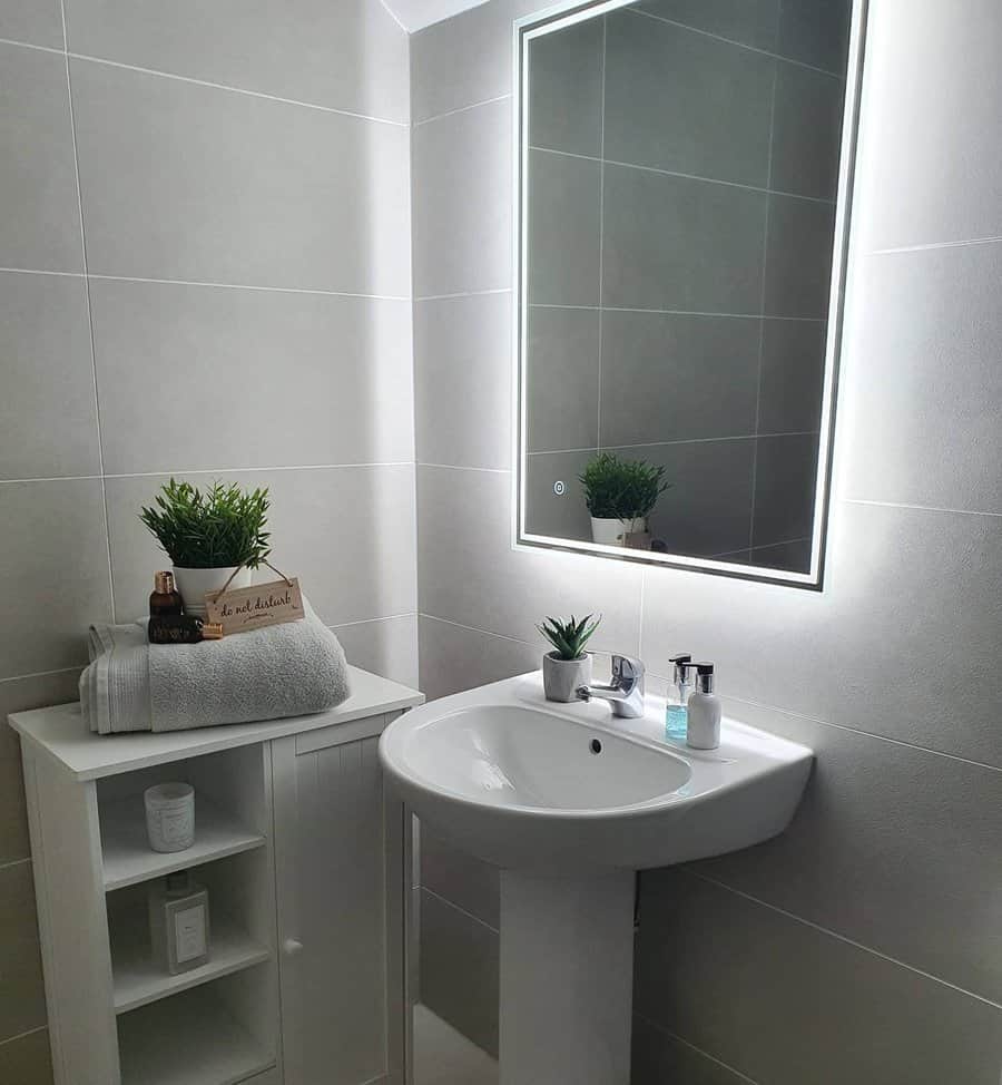 Contemporary bathroom with illuminated mirror and pedestal sink