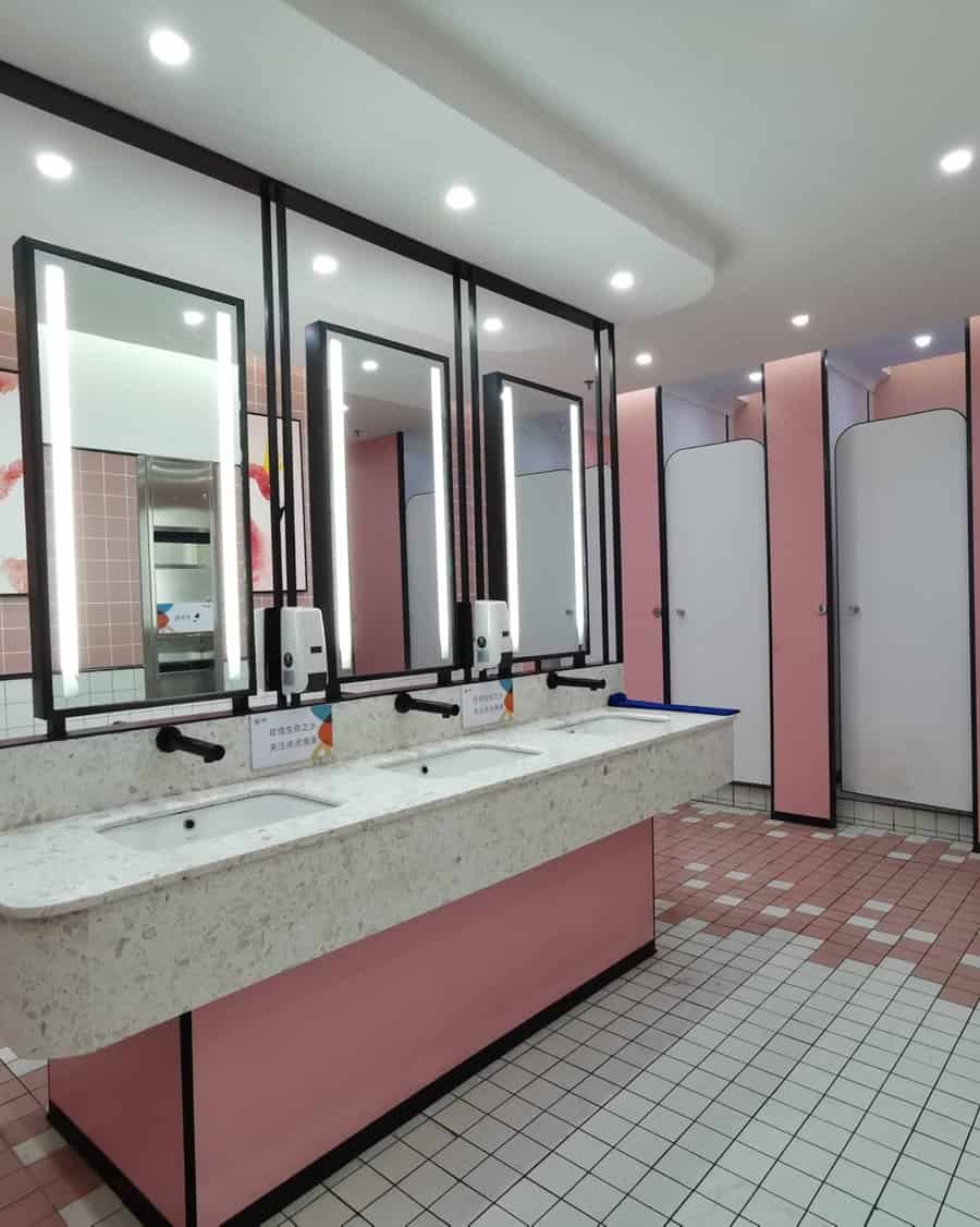 Public restroom with pink partitions and illuminated mirrors