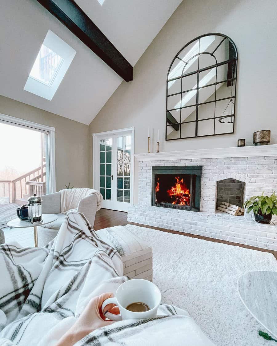 Cozy living room with a wood-burning stove, a round mirror, bookshelves, an armchair with a throw, and decorative items on the mantel