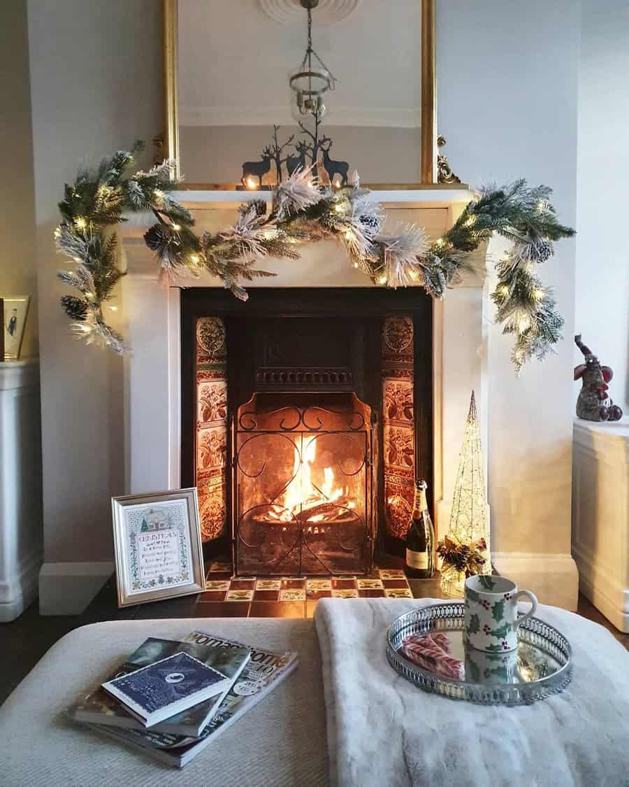 A festive fireplace adorned with a frosty garland, reindeer figurines, and warm lighting, creating a cozy holiday atmosphere with a glowing fire