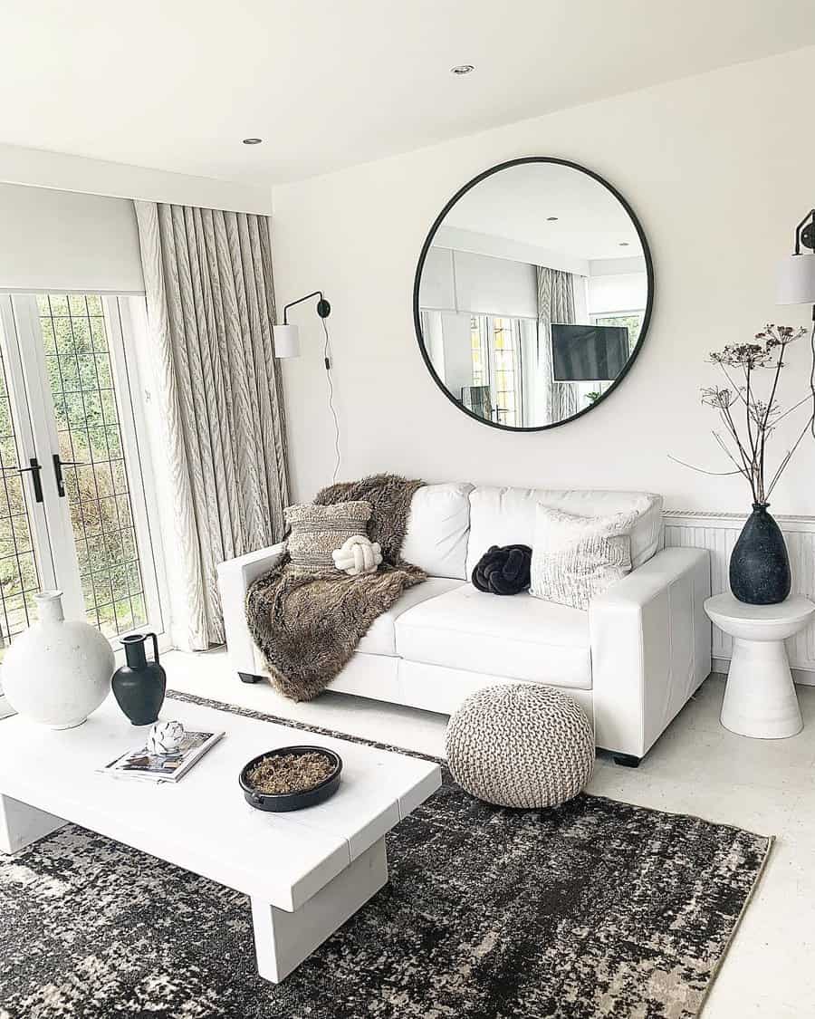 Modern living room with a white sofa, circular mirror, and minimalist decor